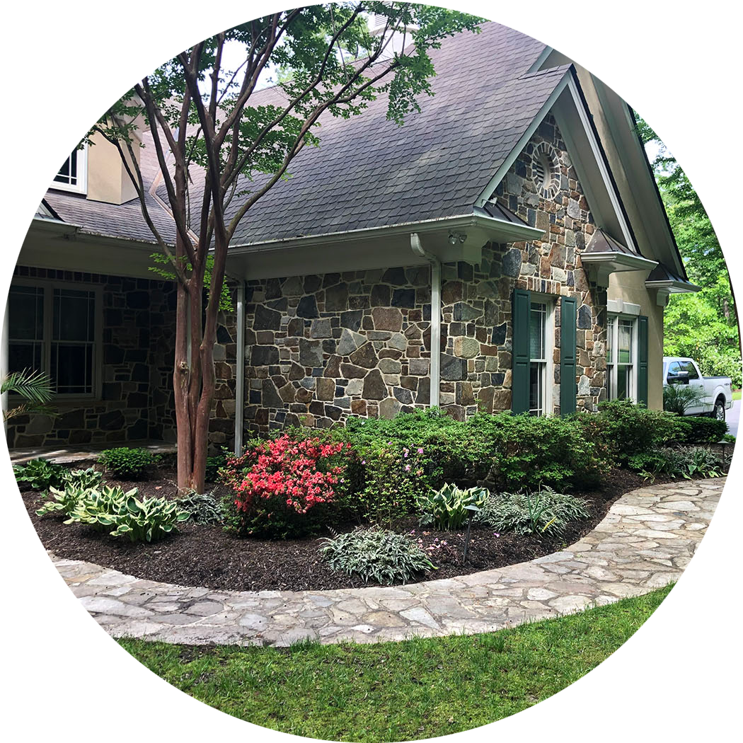 Front of a stone residential house with manicured front garden